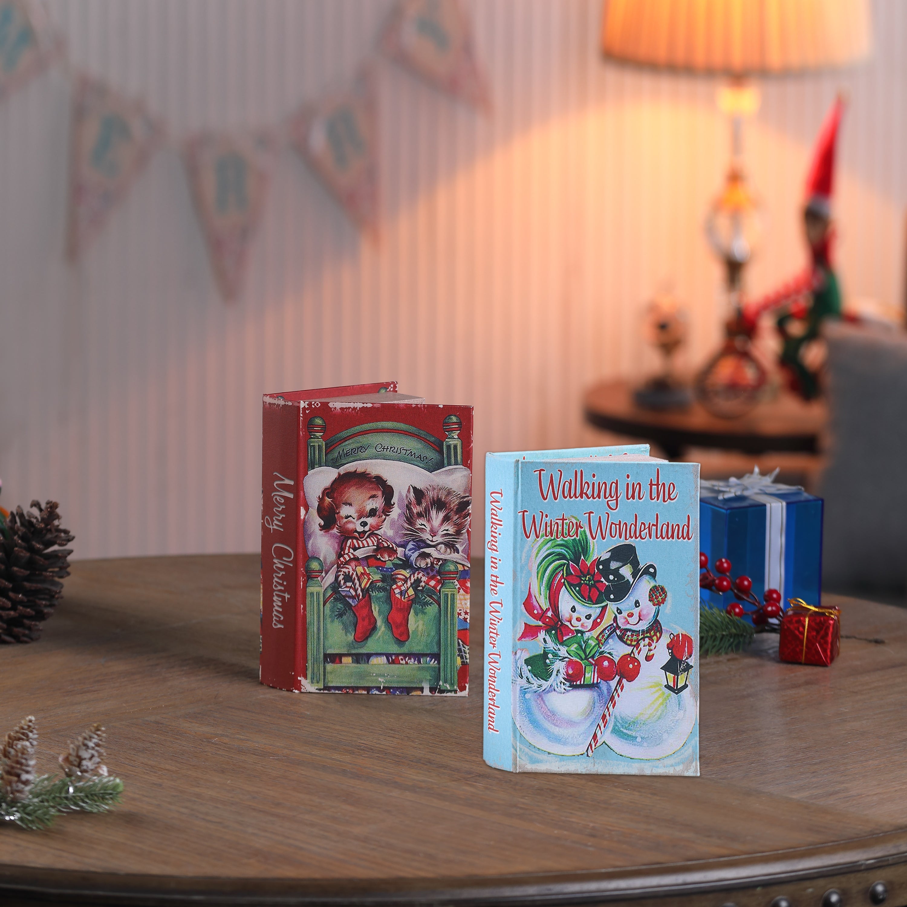 Two miniature Christmas books on a wooden surface with festive decorations.
