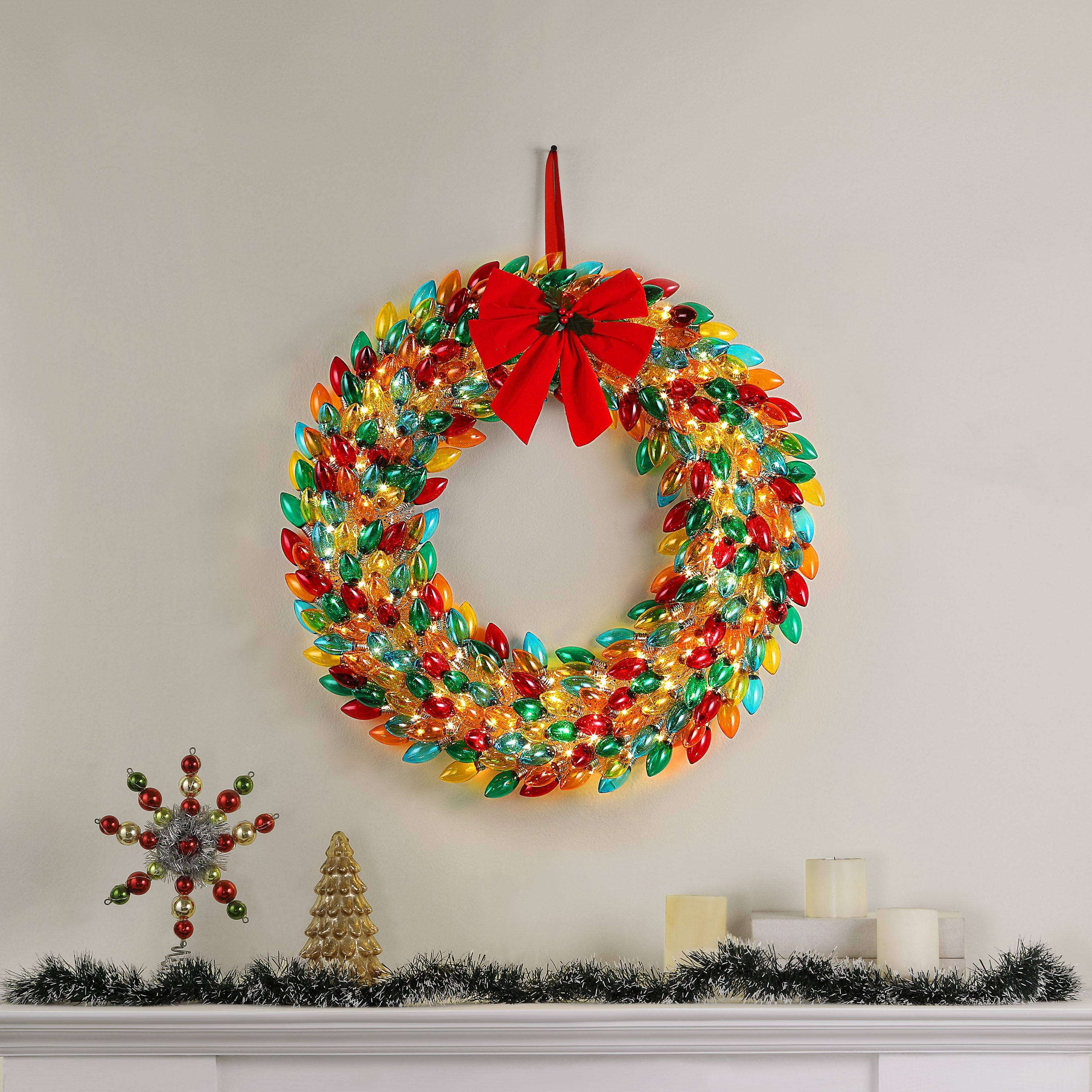 Mr. Christmas 30 in. Retro C9 Bulb Wreath Multi-Color hung on wall with festive decor on a mantel place
