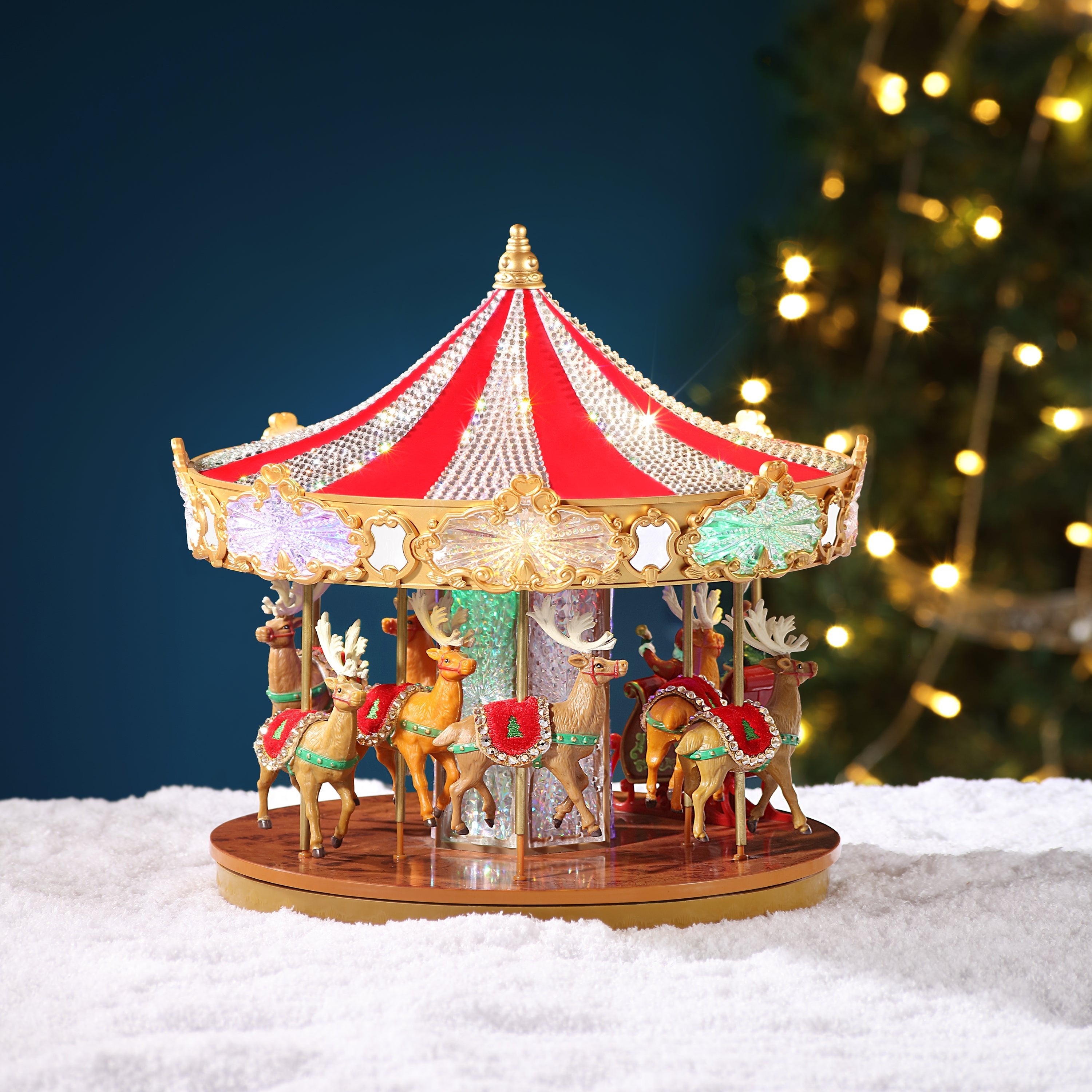 Mr. Christmas Very Merry Christmas Carousel in a snowy setting with a tree in the background showcasing the reindeer in the carousel