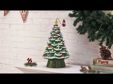 Load video: Animated Santa sleigh circling green ceramic Christmas tree lit with colorful LED bulbs