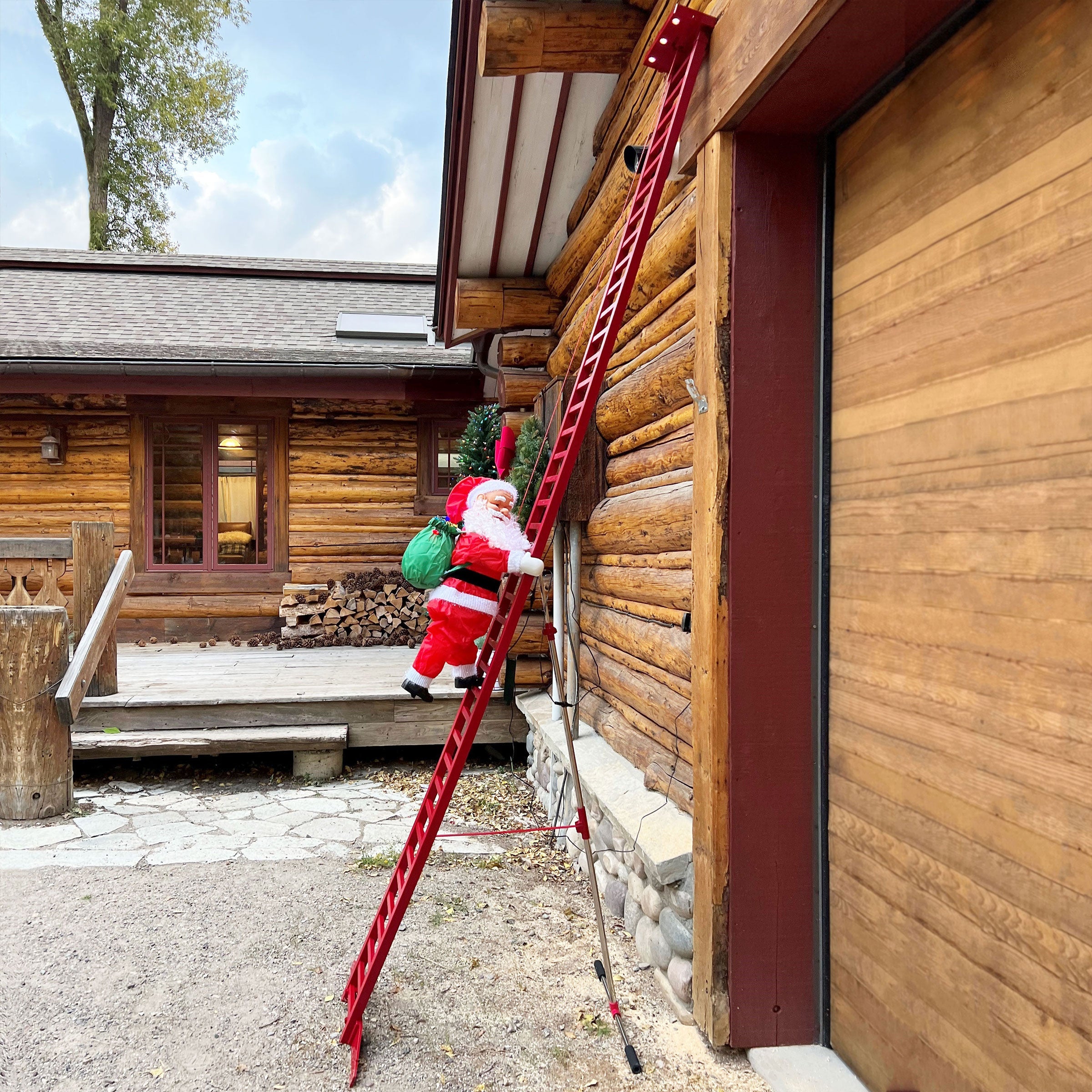 Mr. Christmas 10' Outdoor Animated Super Climbing Santa side view of the ladder Santa displayed against a log cabin house