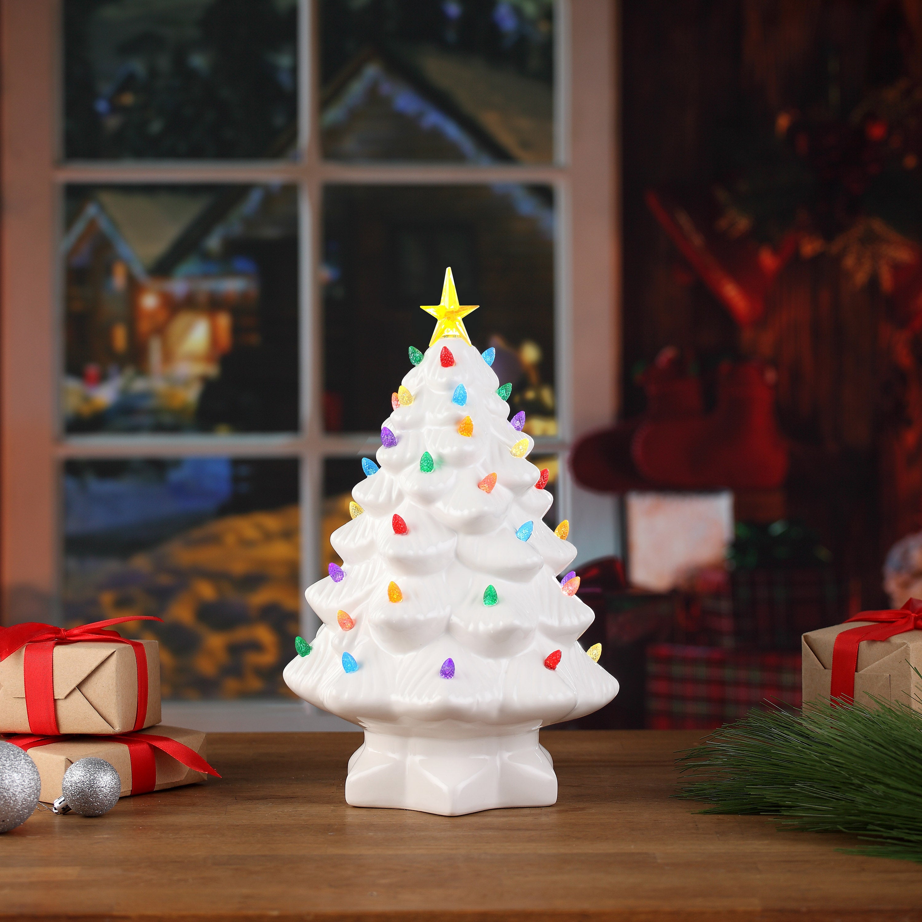 Mr. Christmas 14" White Nostalgic Tree by a window with wrapped presents and festive background decor.