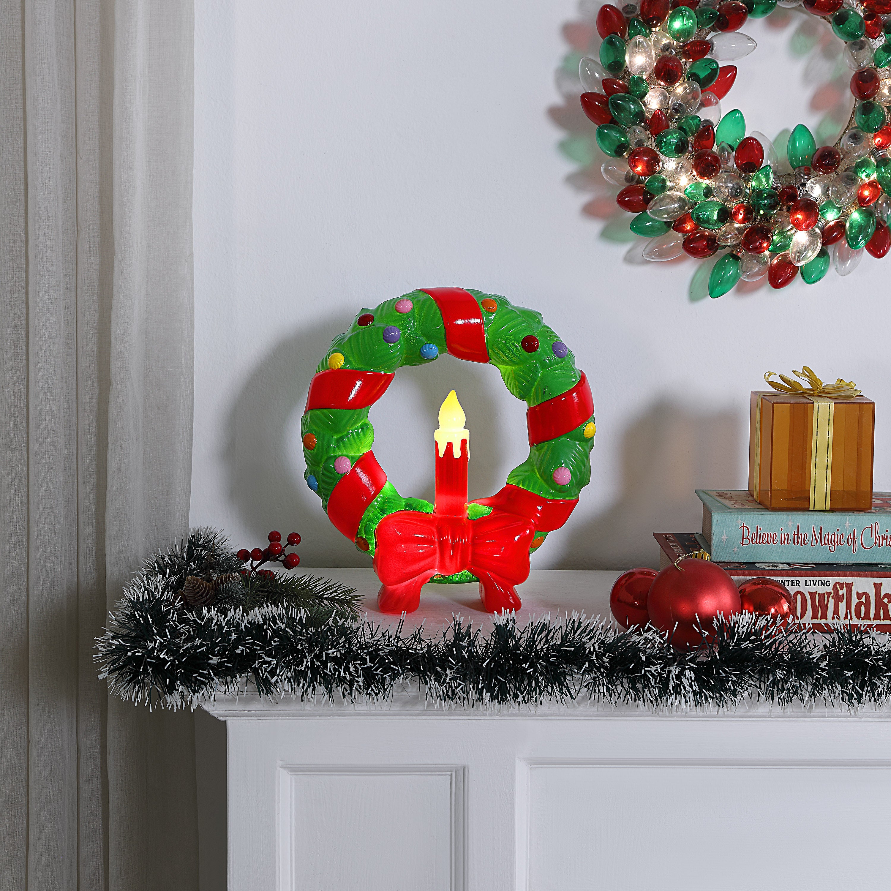 Decorative Christmas in. Lit Blow Mold Wreath with candle on a mantel, wreath and decorations in the background