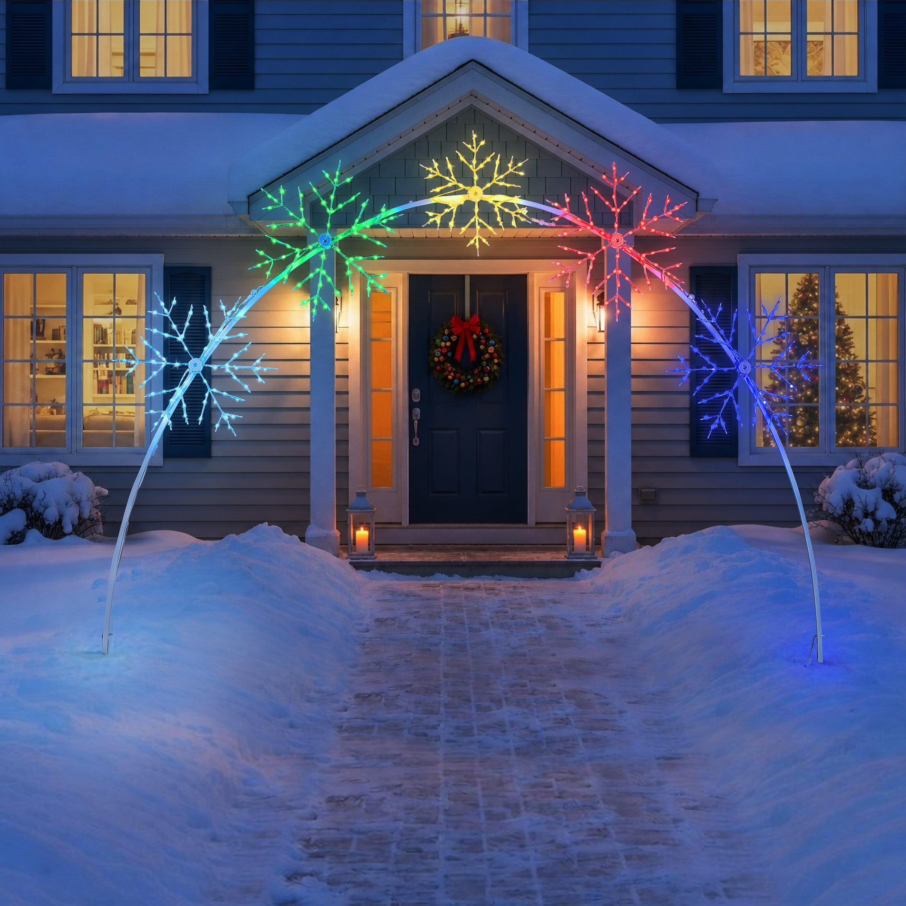 A set of four LED snowflake light arches in blue, green, yellow, and red, displayed on a snowy front porch at night.
