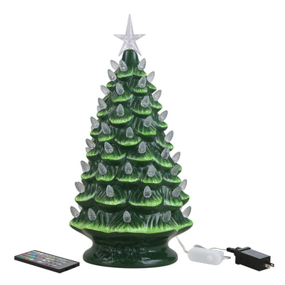 A green ceramic Christmas tree with lit silver-white bulbs, shown with a remote control and power adapter on a white background.