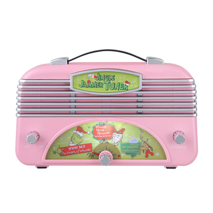 A retro-style grinch pink radio with a black handle and silver metal grille, featuring a green 'Jungle Jammer Tuner' sign and cartoon graphics on the front, set against a plain white background.