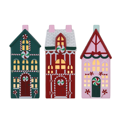 Three Christmas flat ceramic houses with warm white LED lights inside, shown side by side on a plain white background.
