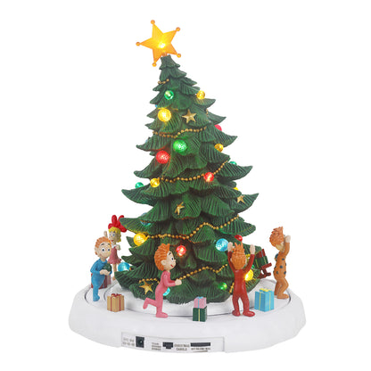 A lit Christmas tree tabletop decoration with a green tree, multicolored ornaments and lights, a glowing gold star on top, and small holiday figures and gifts around the base, shown on a white background.