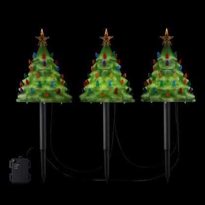 Mr. Christmas Set of 3 Blow Mold Pathway Trees glowing brightly against a dark black background, highlighting the lit LEDs and nostalgic details.