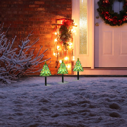 Mr. Christmas Lit Blow Mold Pathway Trees set up outdoors on snowy ground, glowing with multicolor bulbs and illuminated stars.