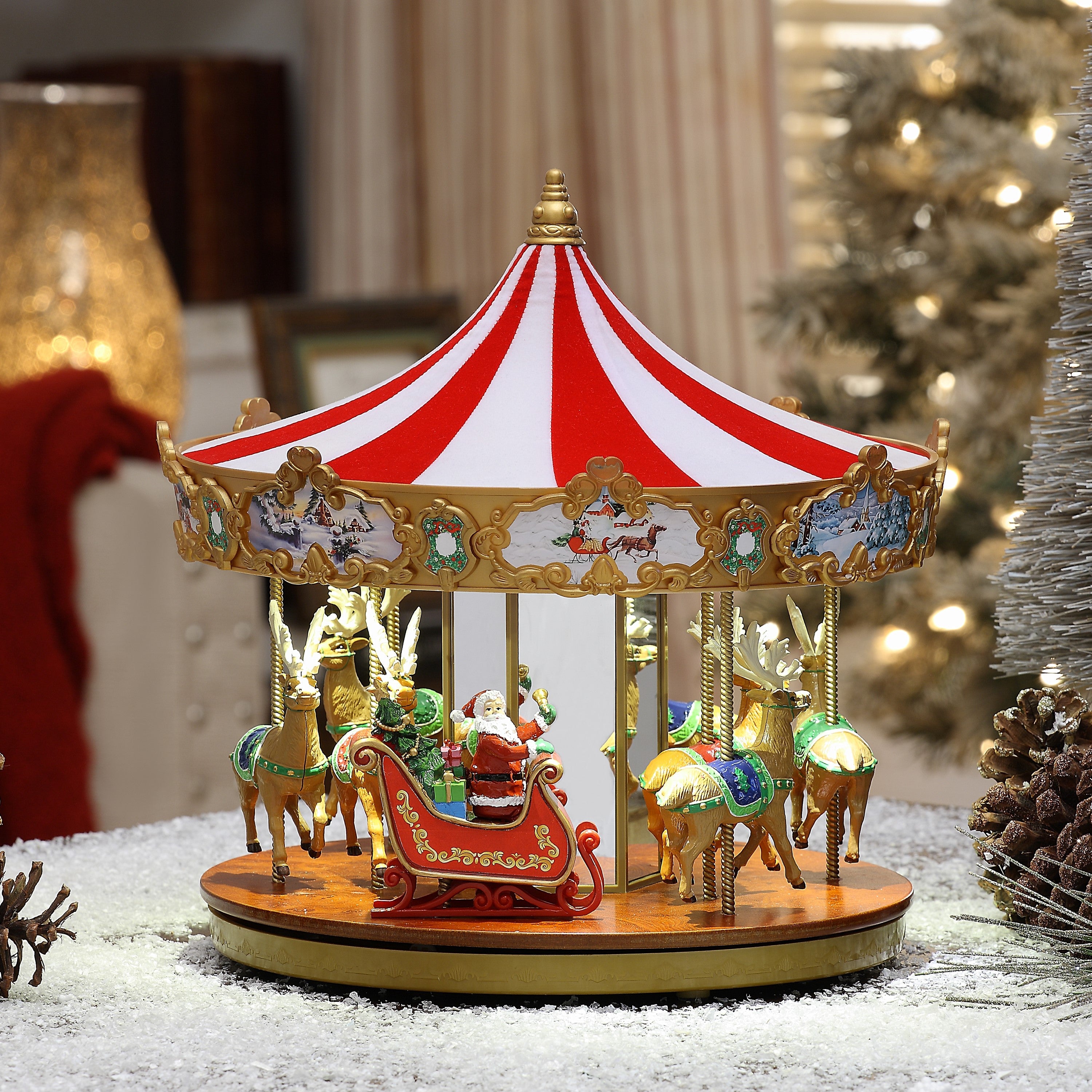 Mr. Christmas 12" Animated Very Merry Carousel lifestyle image displayed on a tabletop with snow and festive holiday decor