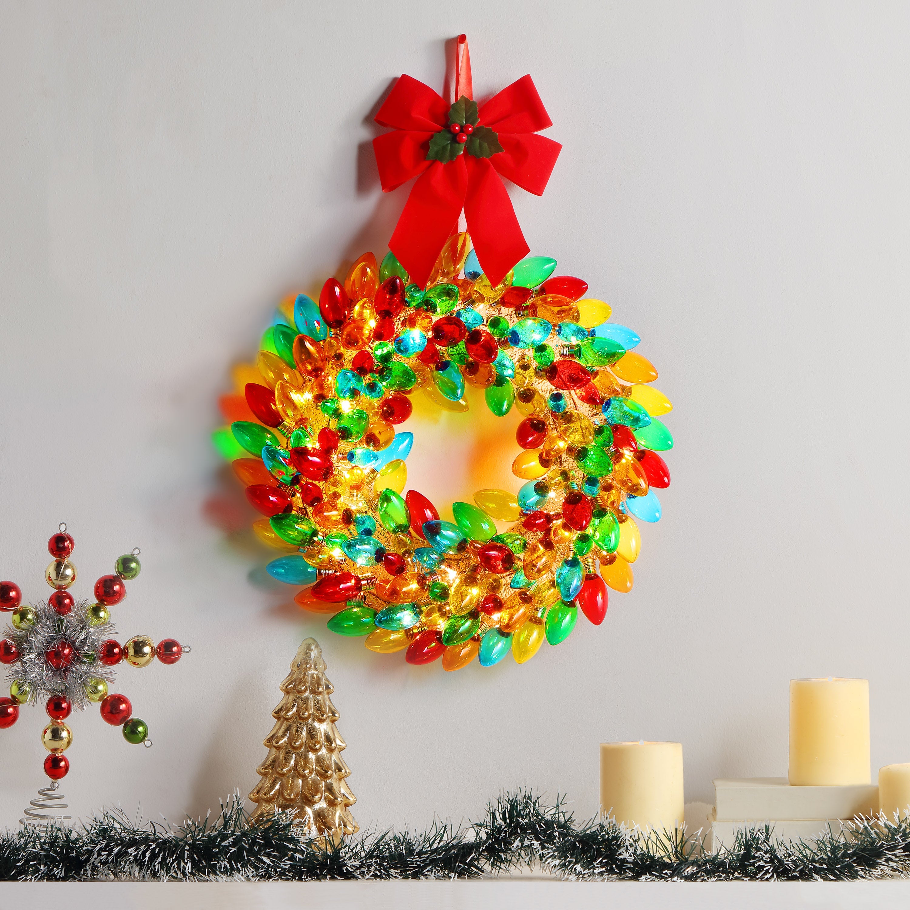 Mr. Christmas 17" Retro C9 Bulb Wreath - Multi-Color Wreath with red ribbon hung on a wall with a festive background with garland 