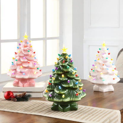 Green Mr. Christmas 14" Nostalgic Tree on a tabletop alongside pink and white ceramic trees